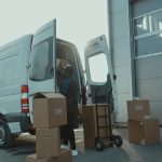 Delivery driver unloading cardboard boxes from a cargo van